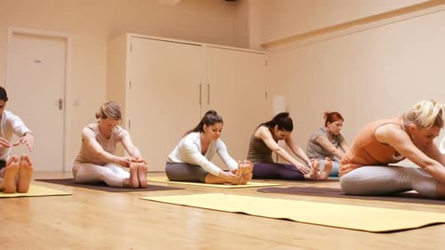 Adults Perform Yoga Seated Forward Bend in Studio