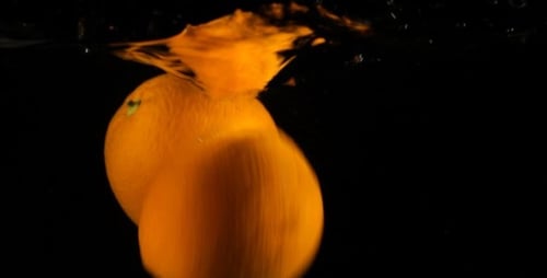 Bright Oranges Falling into Water on Black Background