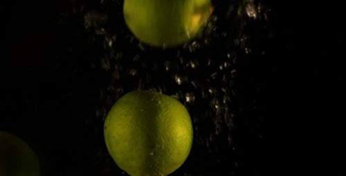 Limes Dropping Into Water in Slow Motion
