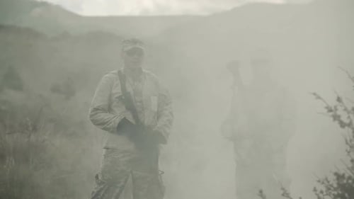 Deux soldats debout dans un nuage de fumée qui se dissipe.