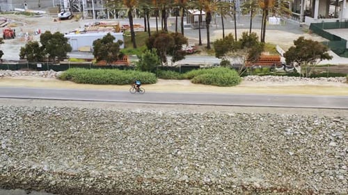 4k aerial rotating drone shot of a man exercising on a 10 speed bike riding to the beach during sunr