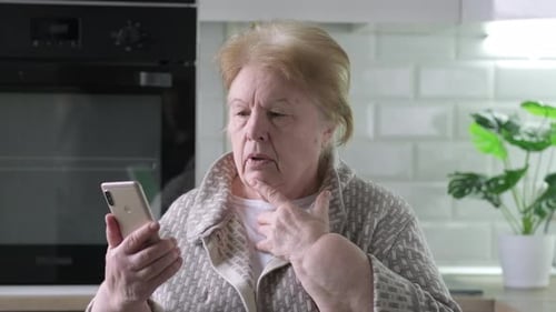 Senior Woman Using Smartphone in Kitchen