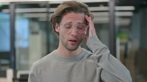 Man With Headache Rubbing Head in Office