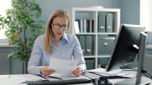 Businesswoman Tearing Up a Piece of Paper at Desk