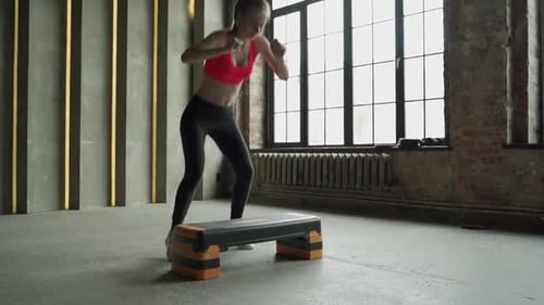 Fit Woman Performing Step Aerobics in Urban Loft