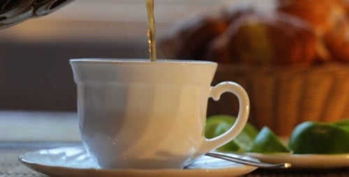 Pouring Tea into a Cup with Croissants