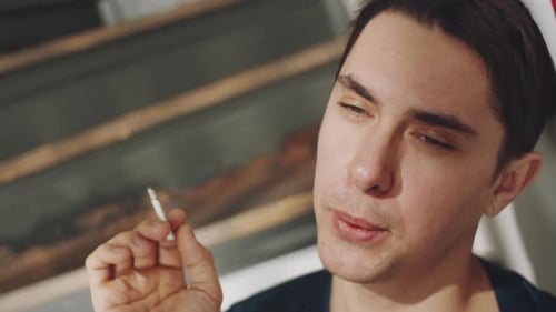 Porträt eines Transgender-Mannes, der zu Hause raucht und trinkt