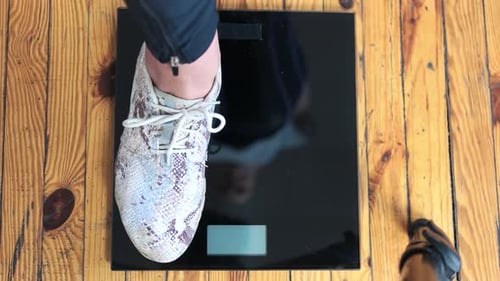 Person Weighing Themselves on Scale at Home