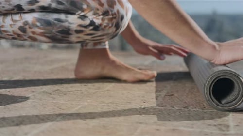 Woman Unrolls Yoga Mat on City Rooftop