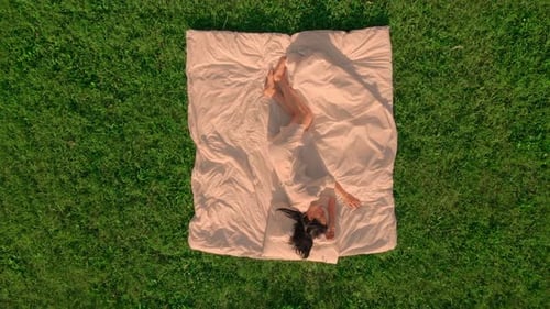 Drone Flying Above Female Lying on the White Bed Meadow with Green Grass