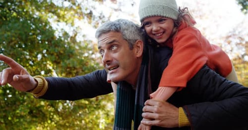 Smiling Father Giving Daughter Piggyback Ride in Park