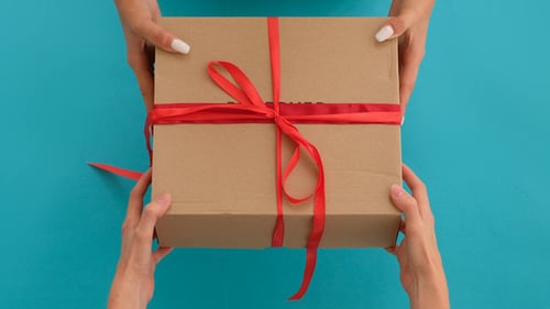 Hands Passing Decorative Gift on Turquoise Background