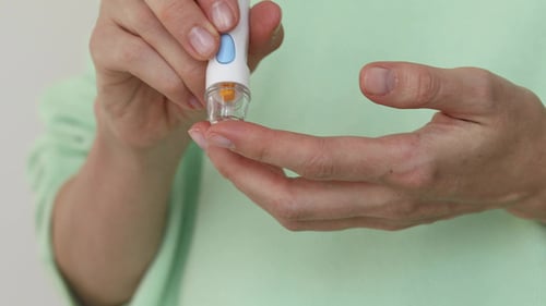 Menina diabética punciona o dedo para medir o sangue