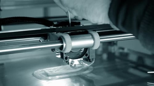 Une imprimante 3D imprime un objet orange en gros plan