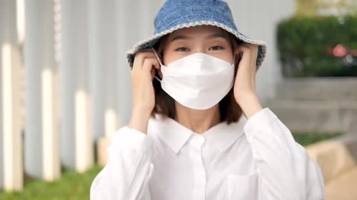 Smiling Woman Putting On Protective Face Mask