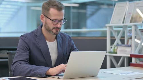 Middle Aged Businessman Working on Laptop in Office in Office
