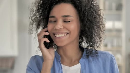 Woman With Curly Hair Talks on Smartphone