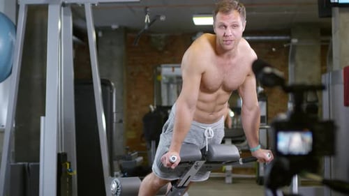 Coach Speaking on Camera and Showing Trunk Raise on Gym Bench