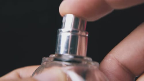 Mann sprüht und verschließt Parfüm in einer Flasche auf dunklem Hintergrund