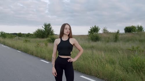 Portrait of Athletic Girl Purposefully Looking at Camera on Road Among Nature