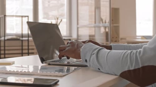 Hands Typing on Laptop Keyboard in Office