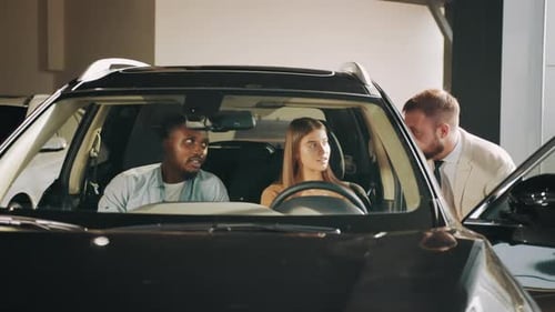 Couple Looking at Car with Salesman in Dealership
