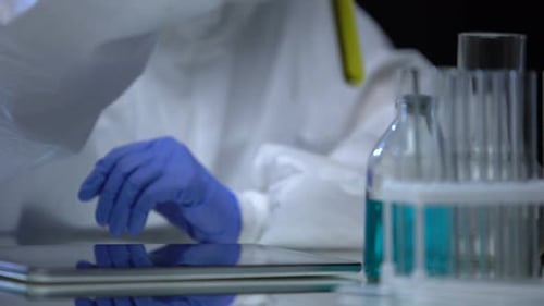 Asistente de laboratorio de combustible que examina el tubo de ensayo con gasolina para sedimentos, control de calidad