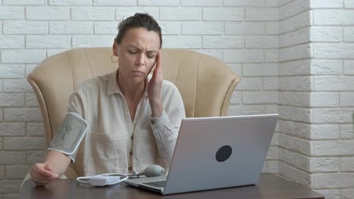 Woman Checks Blood Pressure While Using Laptop