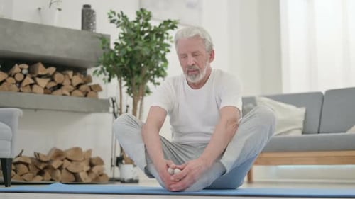 Senior Man Exercising and Stretching on Mat Indoors