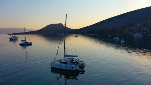 Katamaran- und Segelyachten ankern bei Sonnenaufgang in der Bucht auf tiefblauem Meerwasser