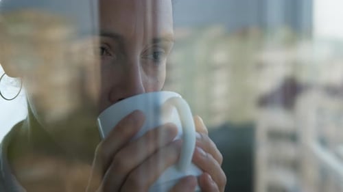 Woman Drinks Coffee in City Apartment Window
