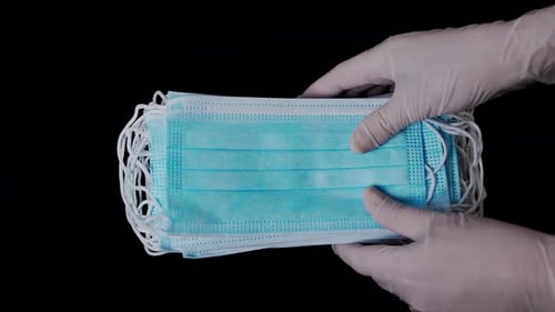 Close Up of Nurse Putting Many Medical Masks on Black Background