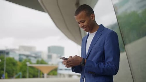 Young Man Types on Phone in Urban Setting