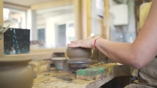 Woman shaping clay into pottery on pottery wheel