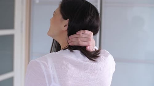 Woman Rubs Back of Neck Indoors