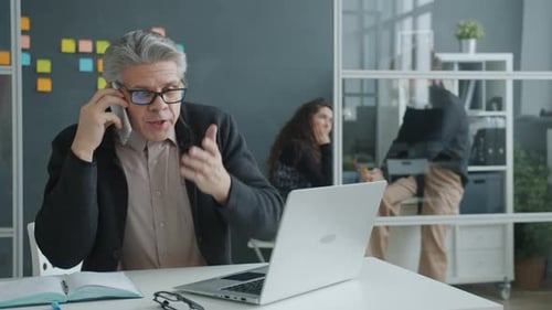 Slow Motion of Angry Man Talking on Mobile Phone Yelling Then Hitting Table in Office