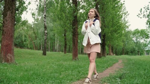 Beautiful Woman Smiles Walking Along Path Surrounded By Foliage and Trees