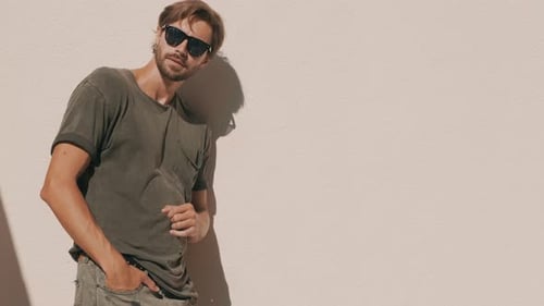 Stylish Man Posing in Sunglasses Against Wall