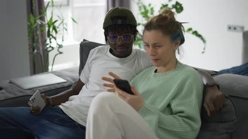 Couple Laughing Together Looking at Smartphone At Home