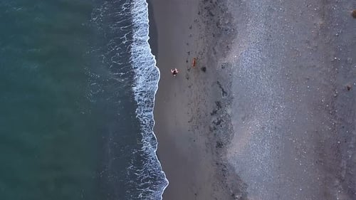Girl and dog walking at the Almeria beach at sunset. Aerial view