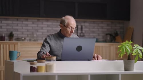 Senior Man Working on Laptop at Home Desk