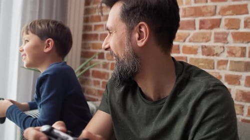 Father and Son Playing Video Game Together at Home