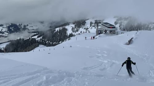 Ein Skifahrer, der auf der Abfahrt Ski fährt und eine Spur auf dem weißen Schnee verlässt - Skigebiet in Österreich während