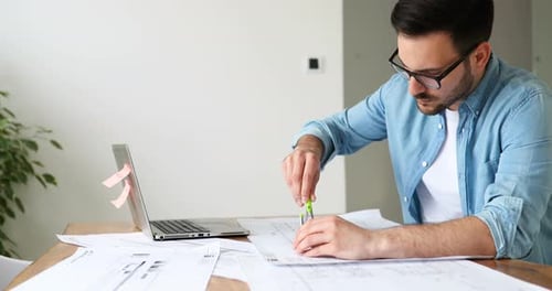Architect Working on Blueprints at Desk Indoors