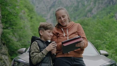Woman and Child Using Tablet Near Car