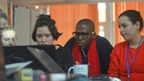 Young International Team Is Working on Online Project at Table in Modern Office Irrl.