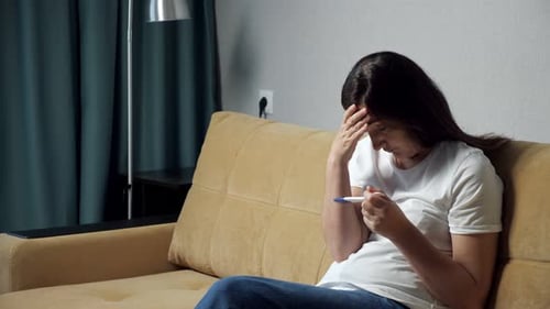 Junge Frau mit Frustration schaut sich den Schwangerschaftstest an