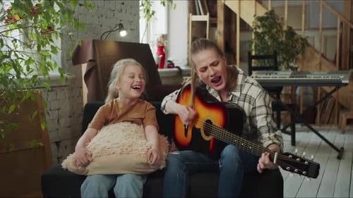 Woman Plays Guitar and Sings with Child