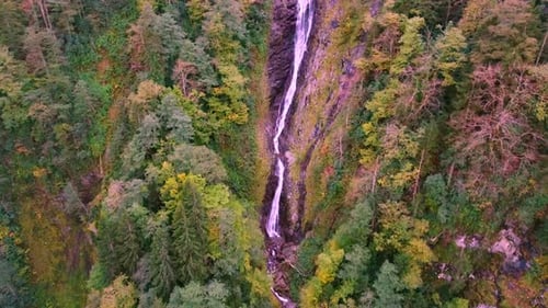 Der Wasserfall fließt zwischen den Herbstfarben