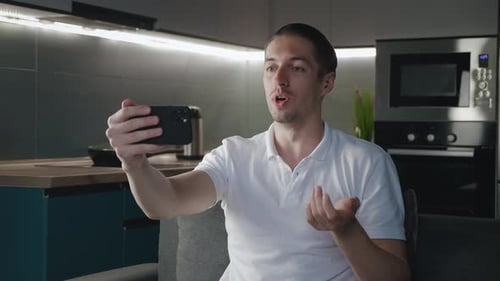 Smiling man video chatting on phone in kitchen